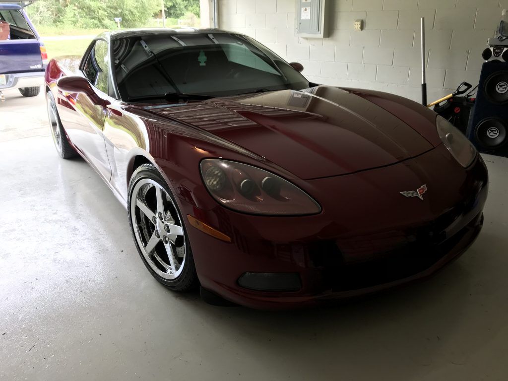 A red corvette is parked in a garage.