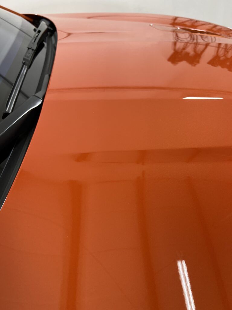A close up of the hood of an orange car