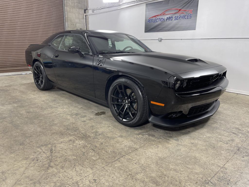 A black dodge challenger is parked in a garage.
