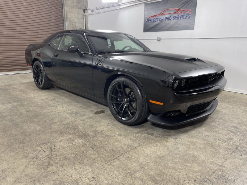 A black dodge challenger is parked in a garage.