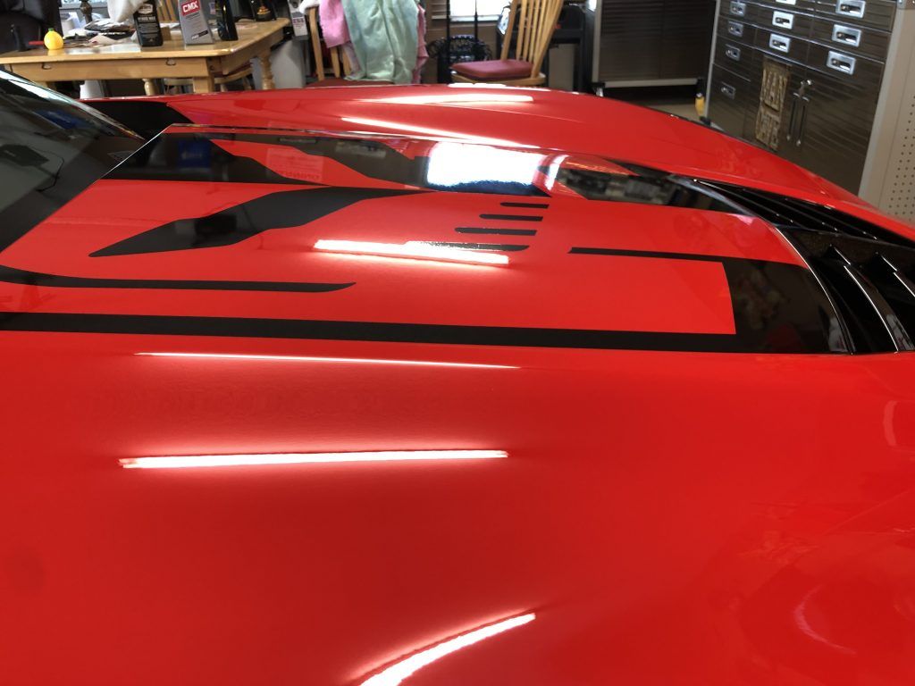 A close up of the hood of a red sports car in a garage.