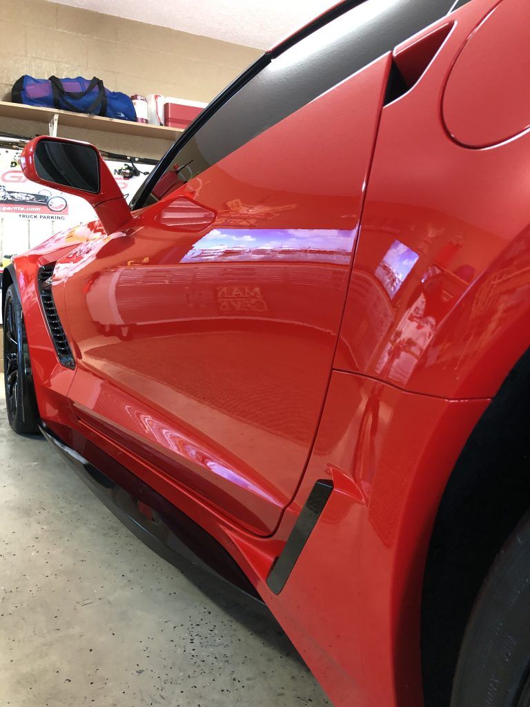 A red sports car is parked in a garage.