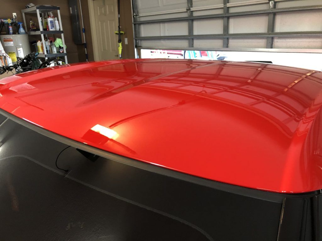 A red car is parked in a garage next to a garage door.