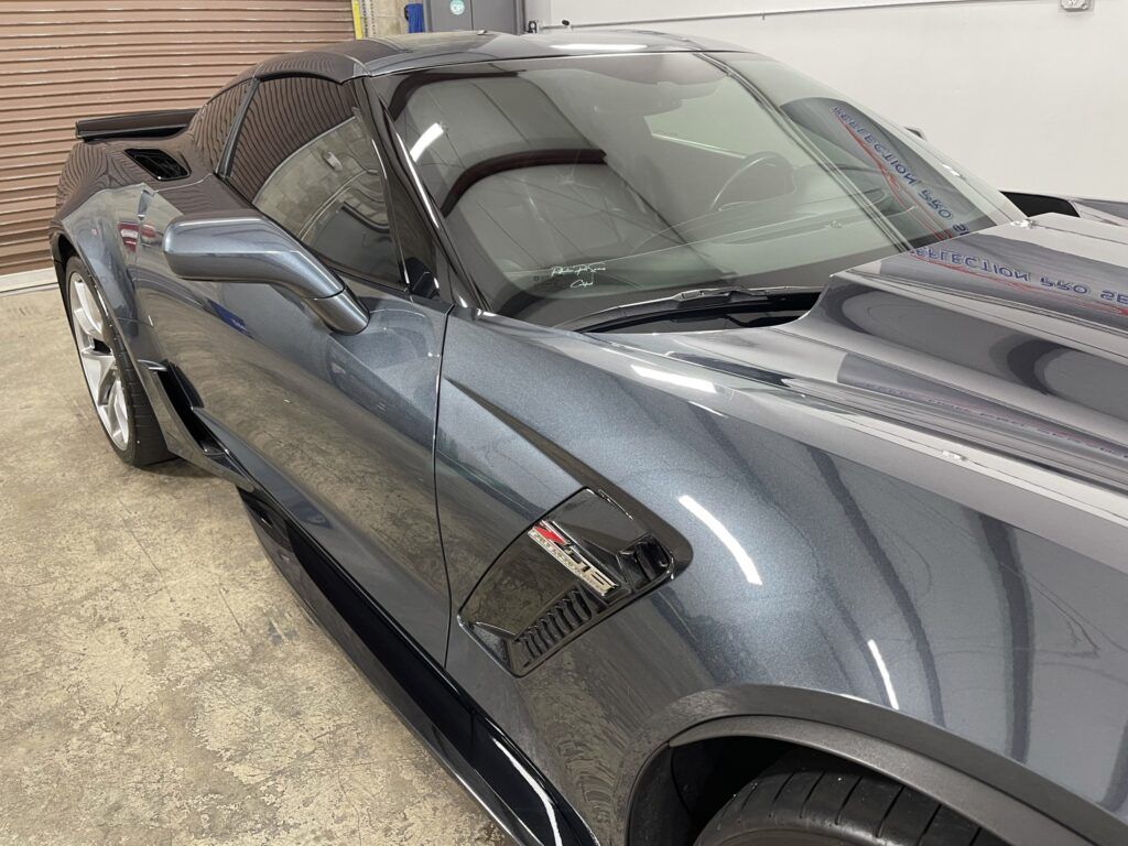 A black sports car is parked in a garage.
