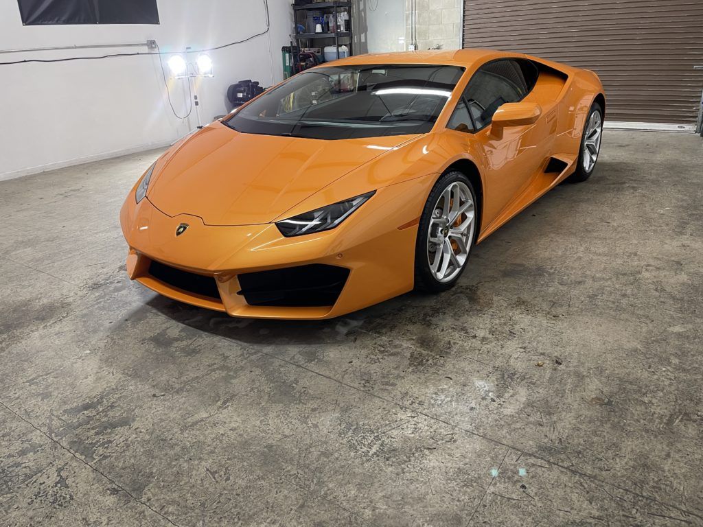 An orange lamborghini huracan is parked in a garage.