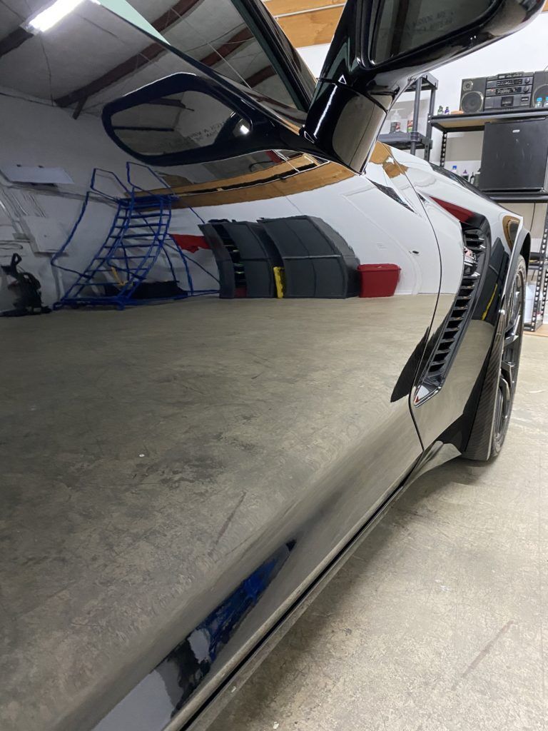 A car is parked in a garage with its door open.