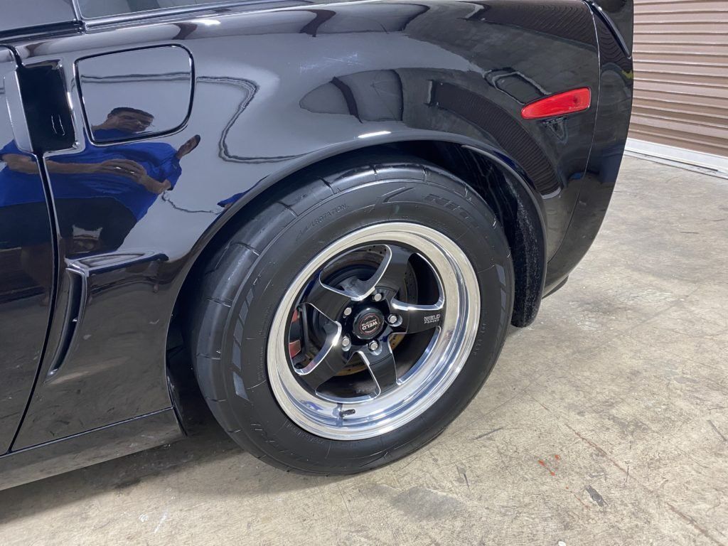 A close up of a black car 's wheel and tire.