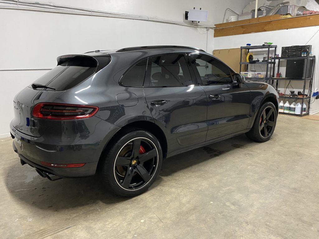 A gray porsche macan is parked in a garage.