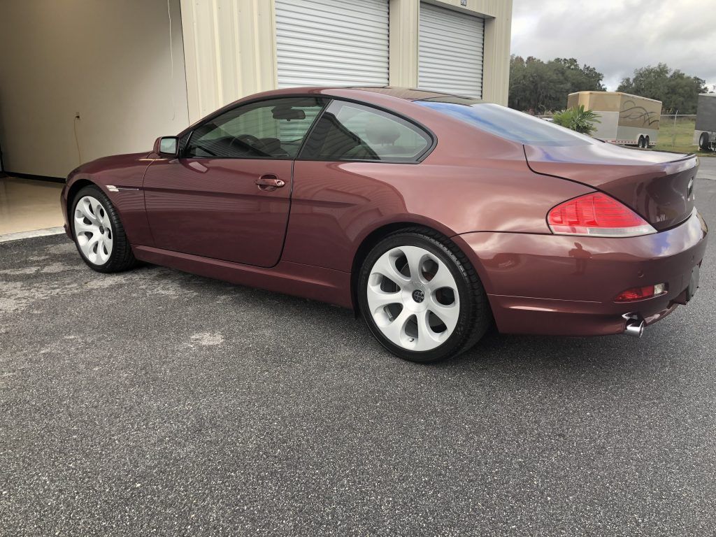 A maroon bmw 6 series coupe is parked in a parking lot.