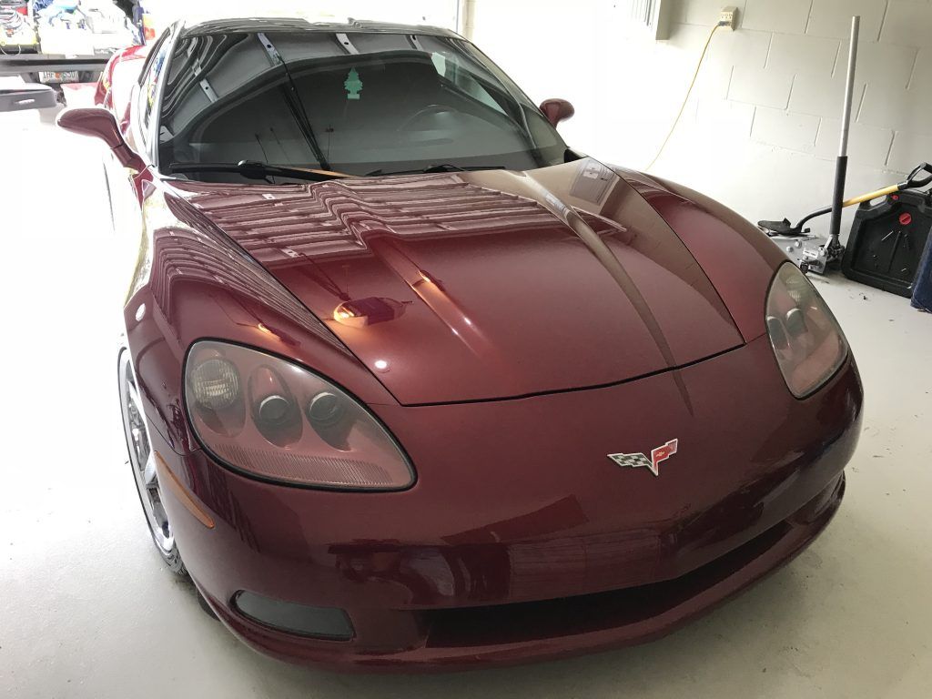 A red corvette is parked in a garage
