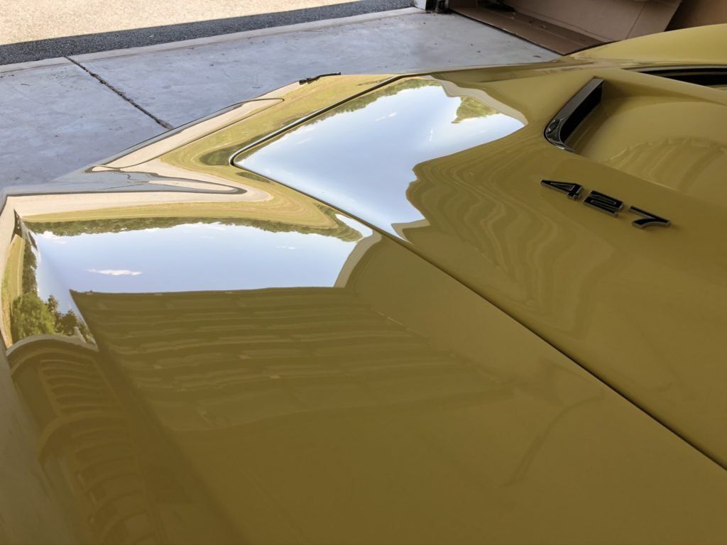 A close up of the hood of a yellow car