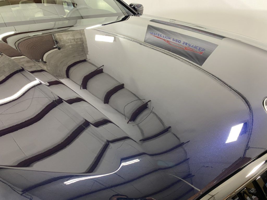 The hood of a car is reflected in the windshield.