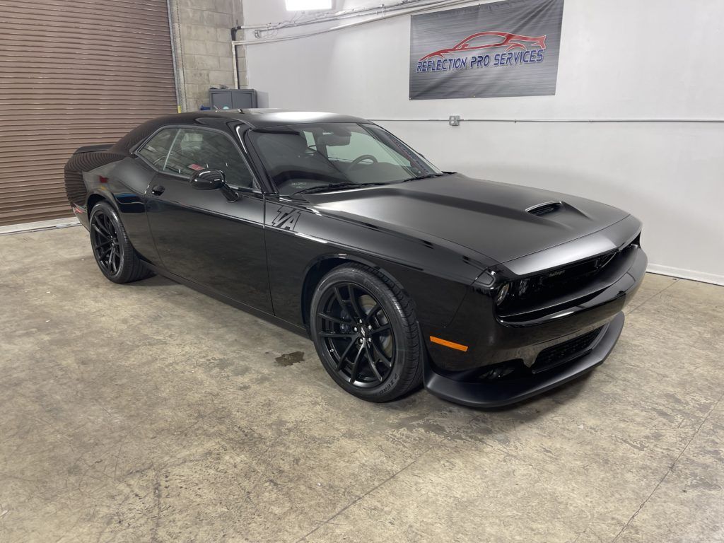 A black dodge challenger is parked in a garage.