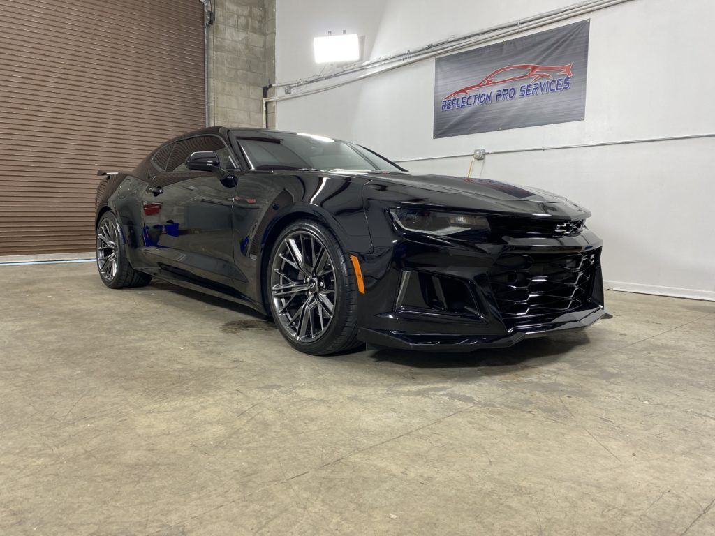 A black chevrolet camaro zl1 is parked in a garage.