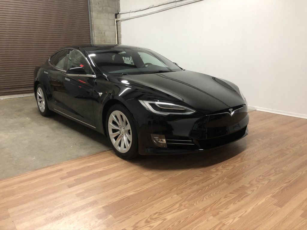A black tesla model s is parked in a garage.