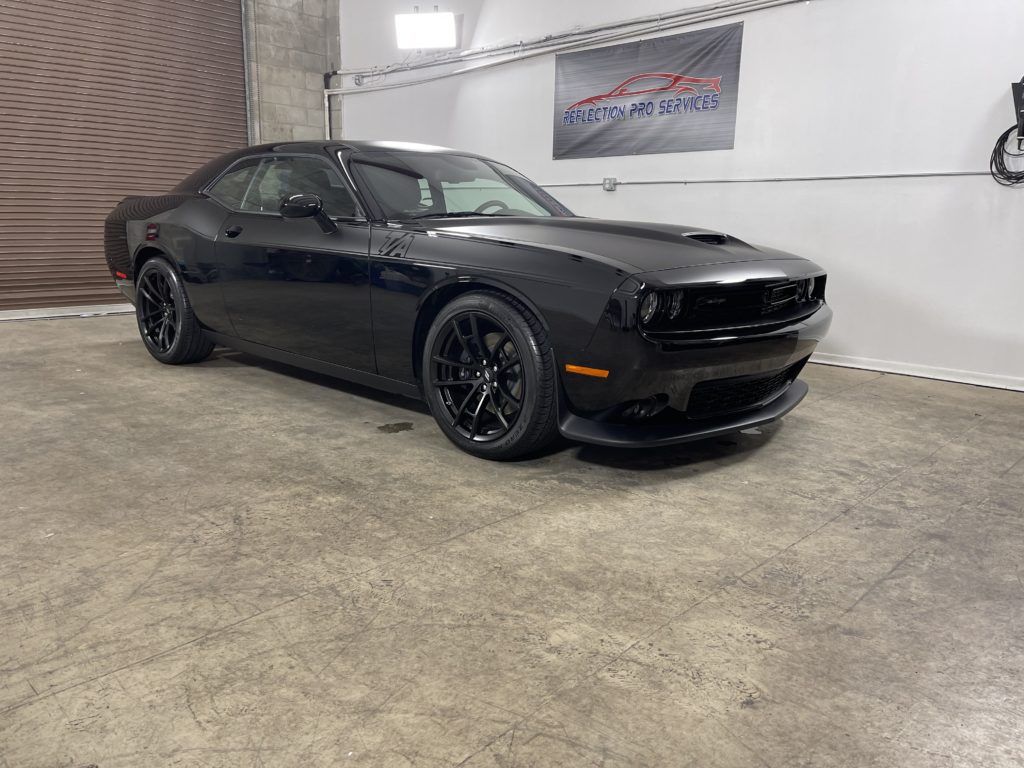 A black dodge challenger is parked in a garage.