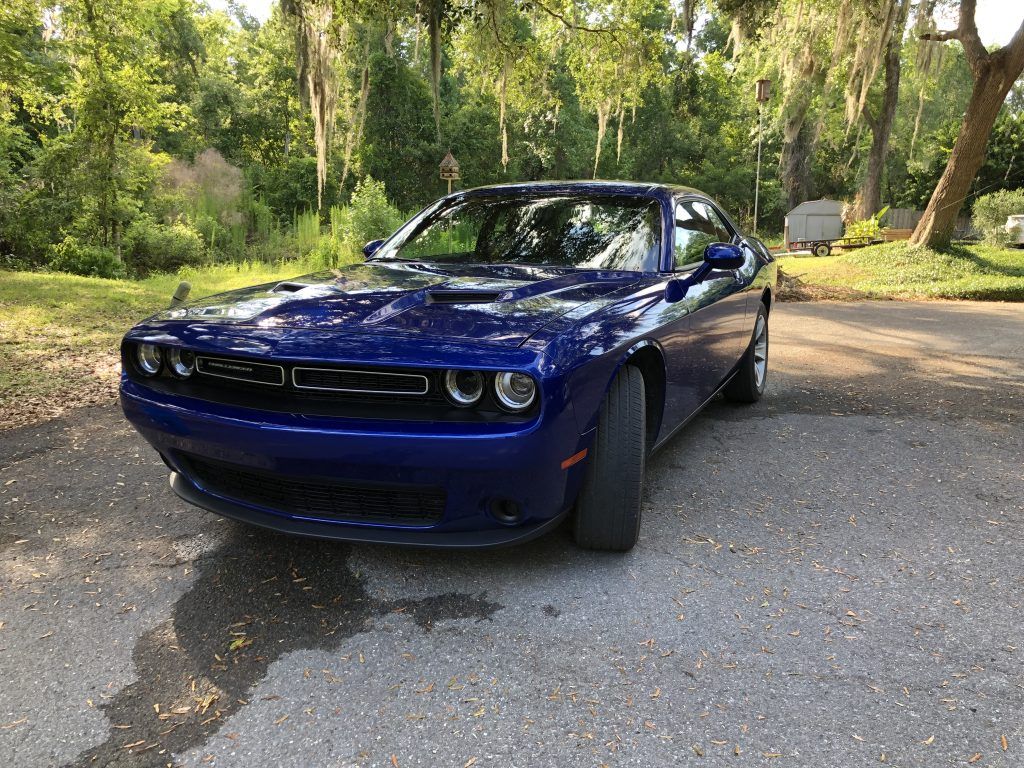A blue dodge challenger is parked on the side of the road.