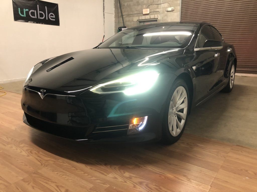 A black tesla model s is parked in a garage.