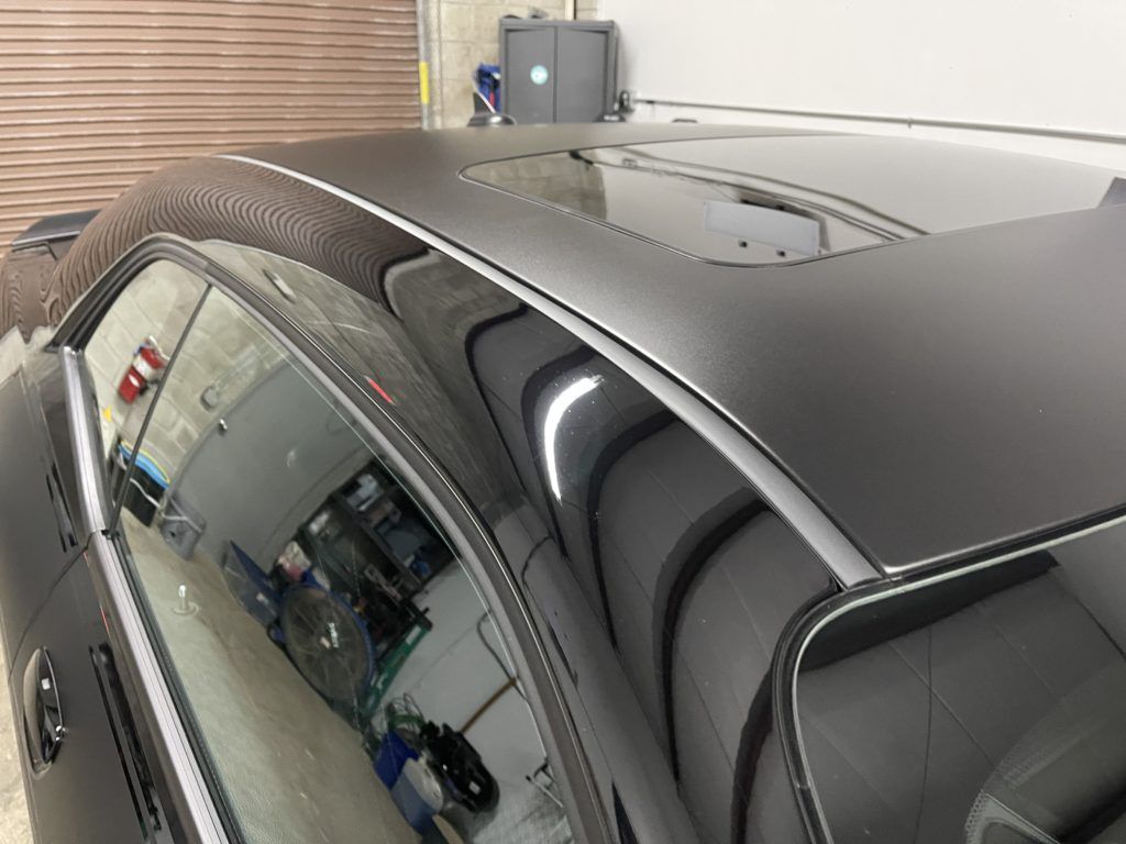 A black car with a sunroof is parked in a garage.