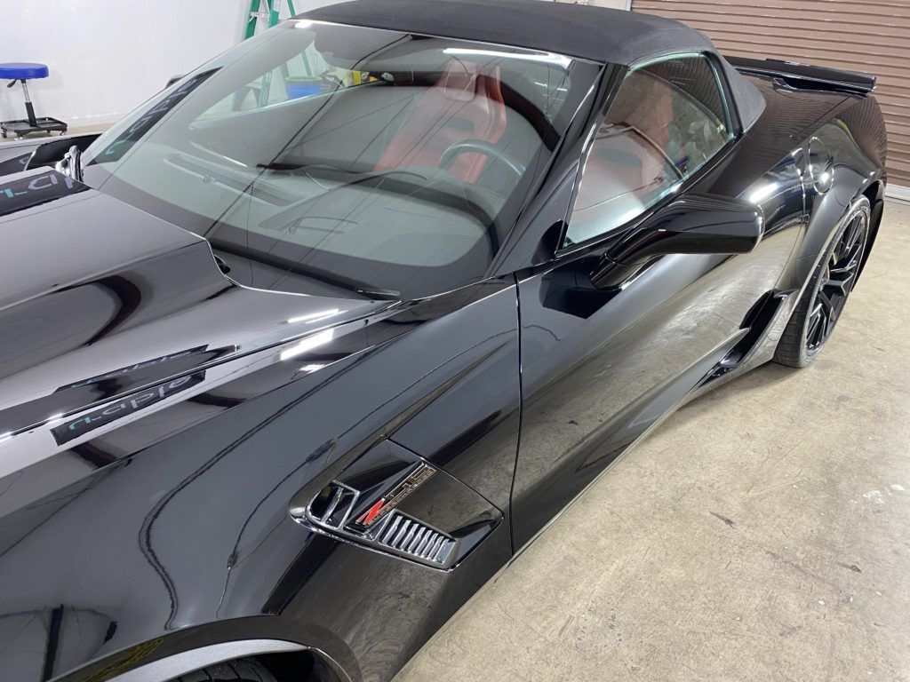 A black sports car with a red seat is parked in a garage.