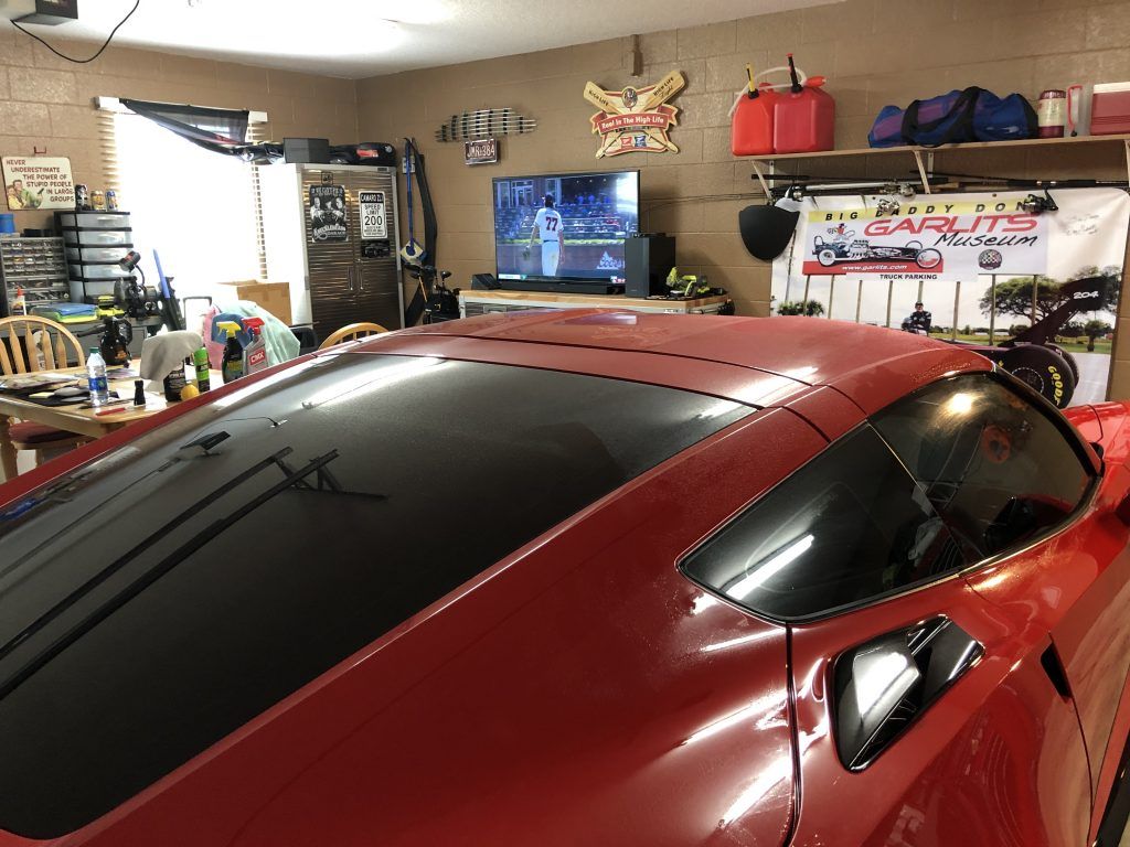 A red sports car is parked in a garage