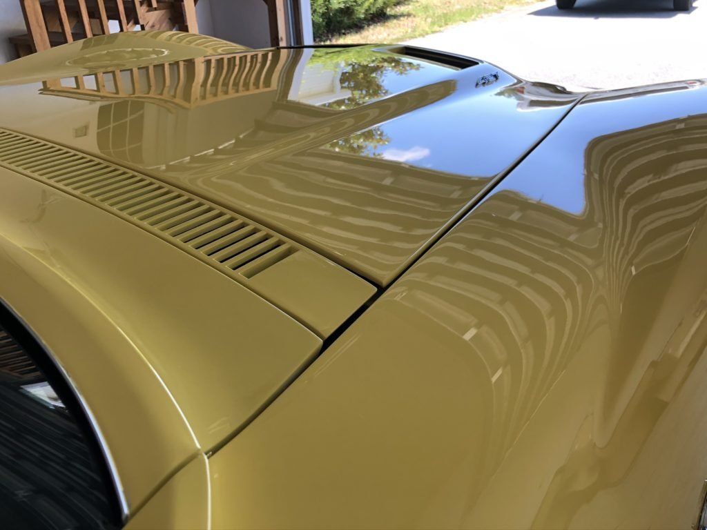 A close up of the hood of a yellow car in a garage.