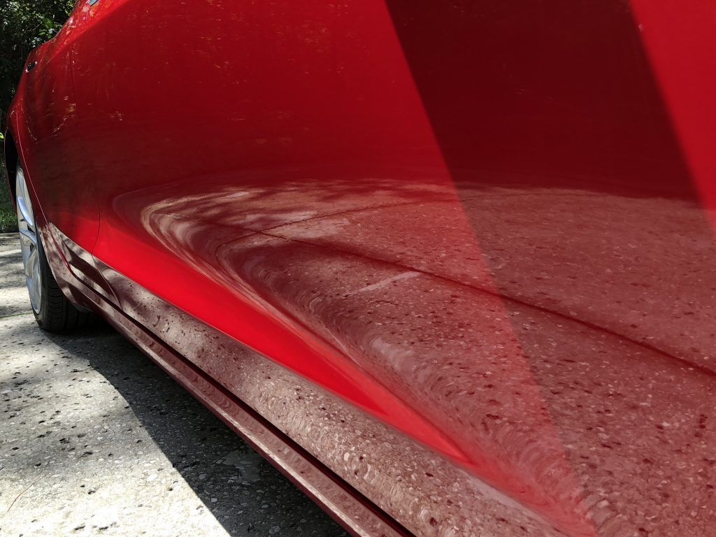 A red car is parked on the side of the road.