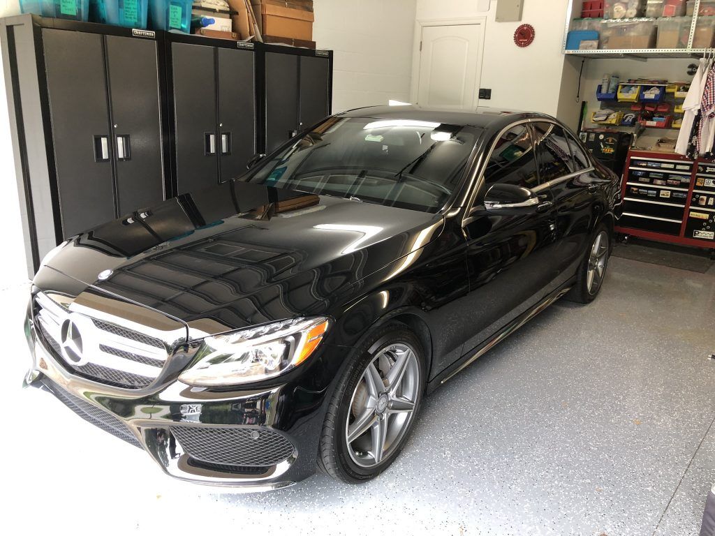 A black mercedes benz is parked in a garage.