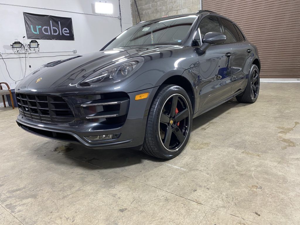 A gray porsche macan turbo is parked in a garage.