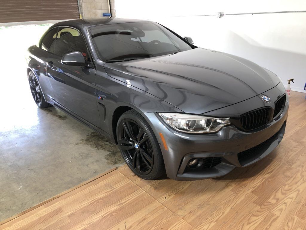 A gray bmw 4 series convertible is parked in a garage.