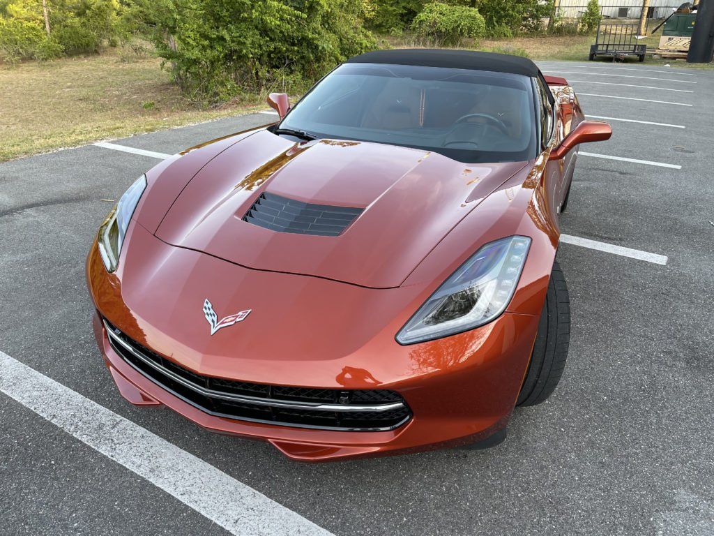 A red corvette convertible is parked in a parking lot.