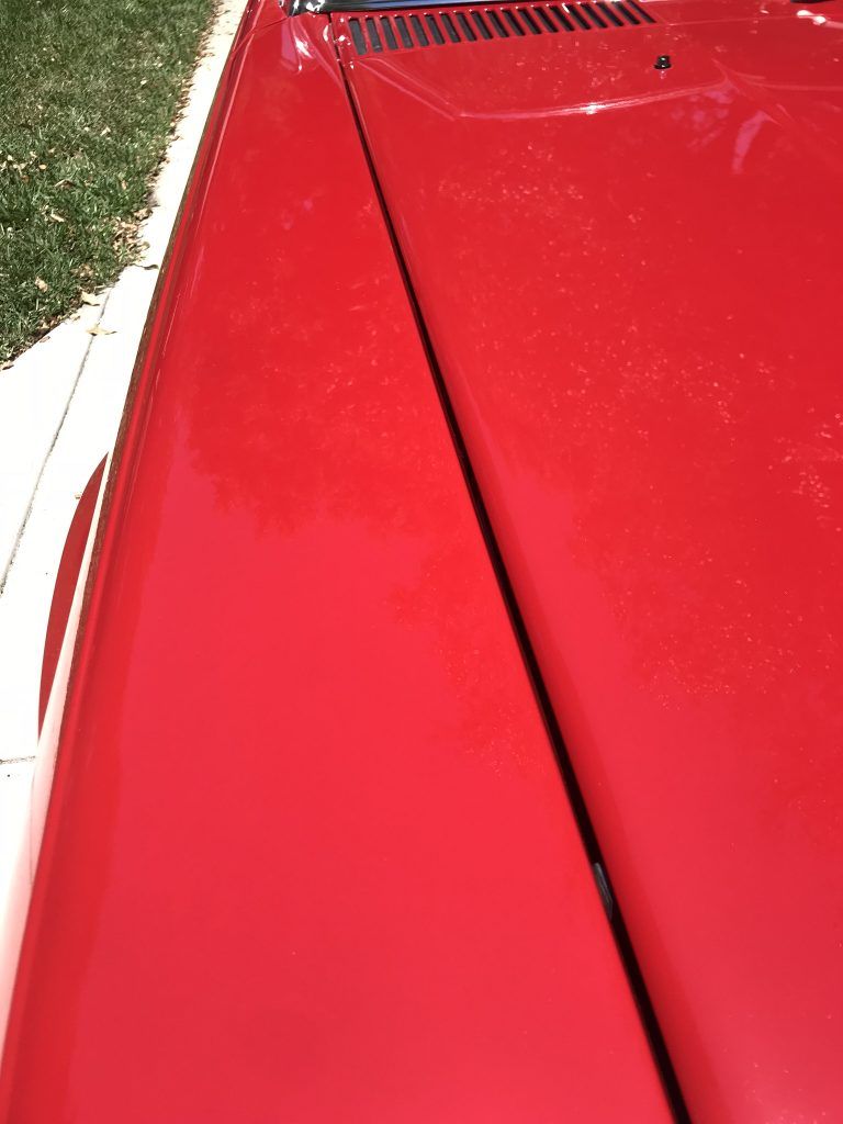 A close up of the hood of a red car