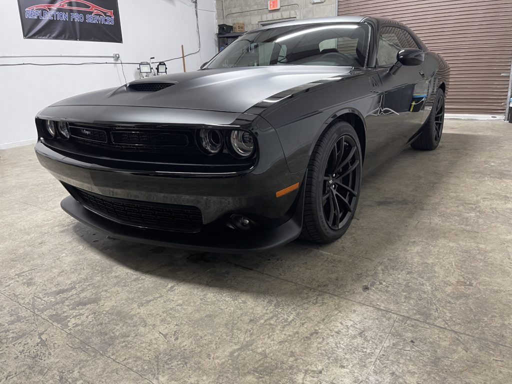 A black dodge challenger is parked in a garage.