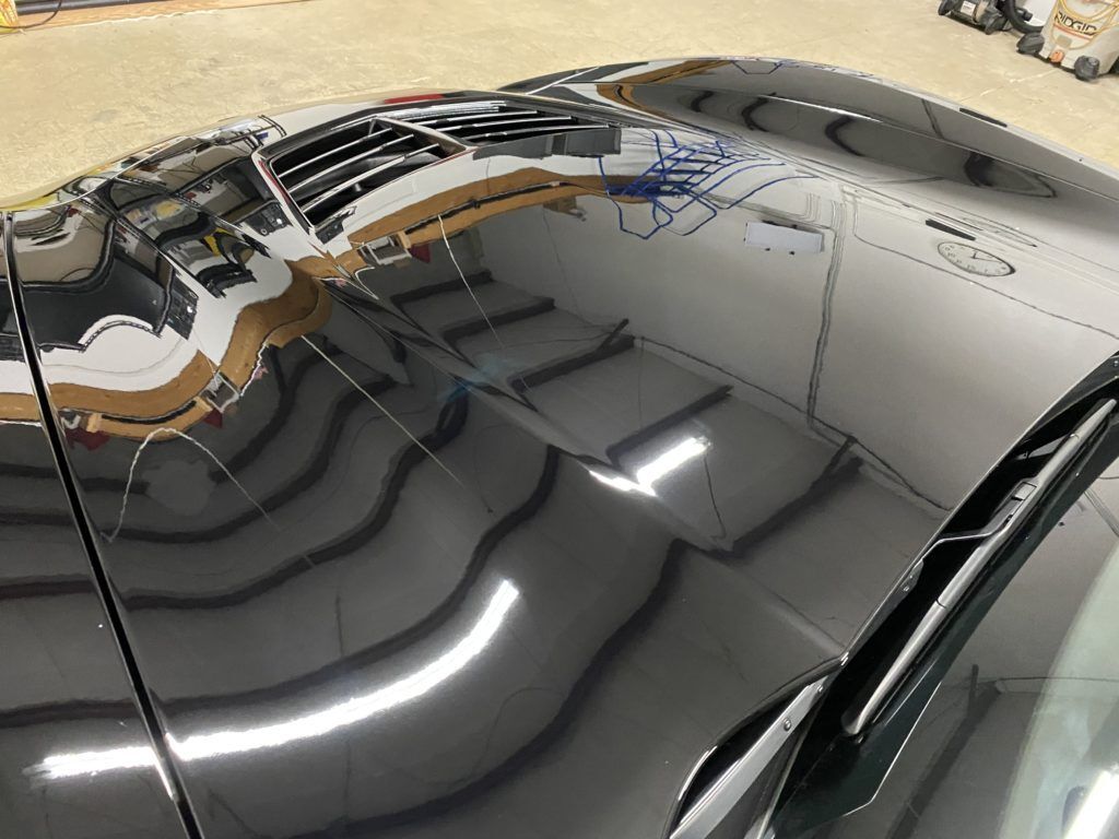 A close up of the hood of a black car in a garage.