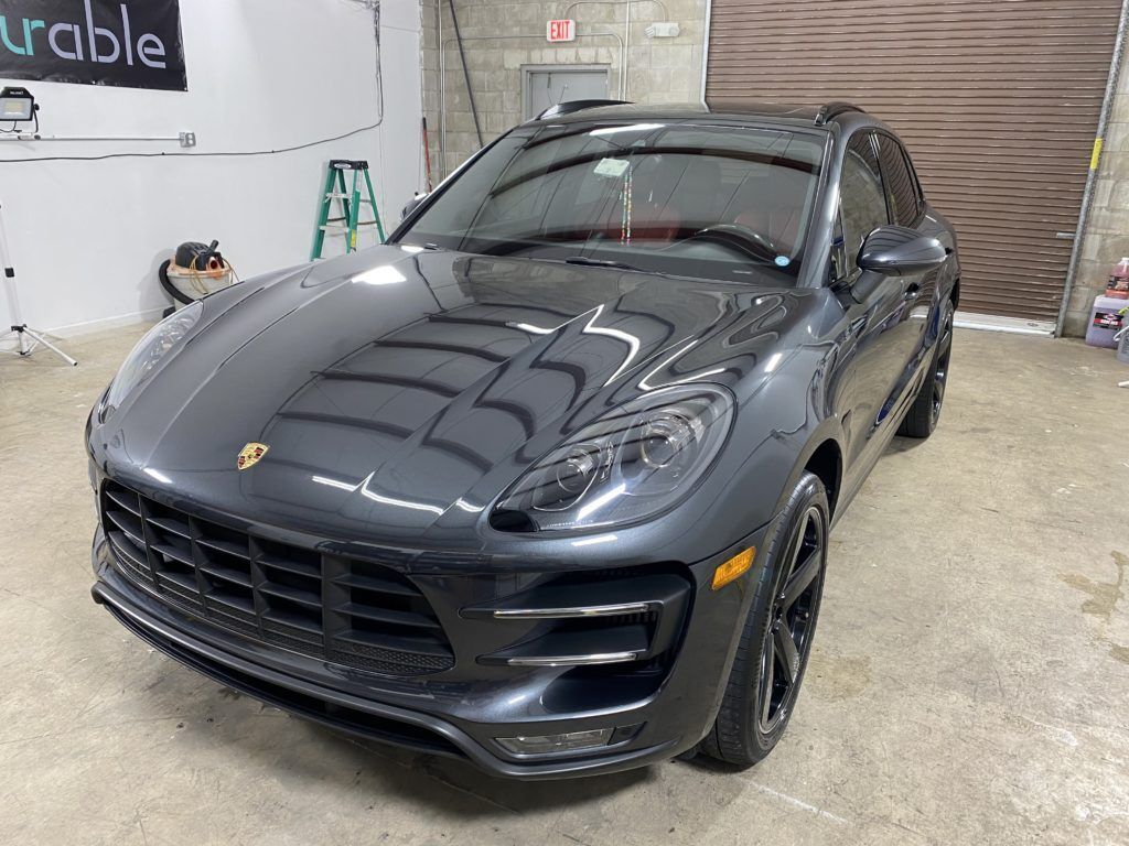 A gray porsche macan turbo is parked in a garage.