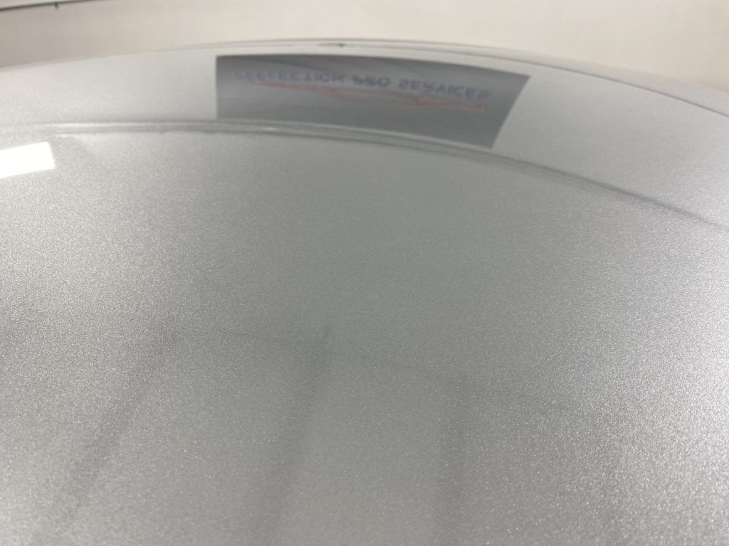 A close up of a white surface with a reflection of a sign on it.