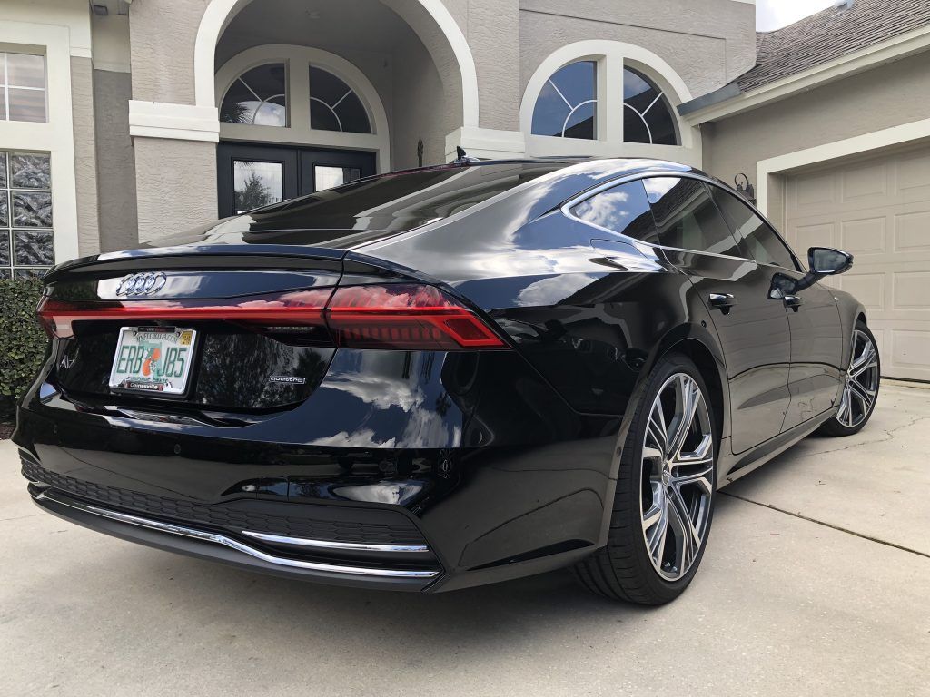 A black car is parked in front of a house.