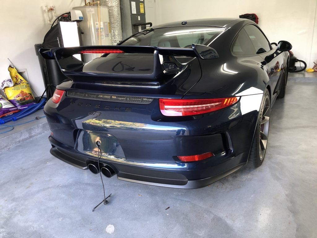 A black porsche 911 gt3 is parked in a garage.