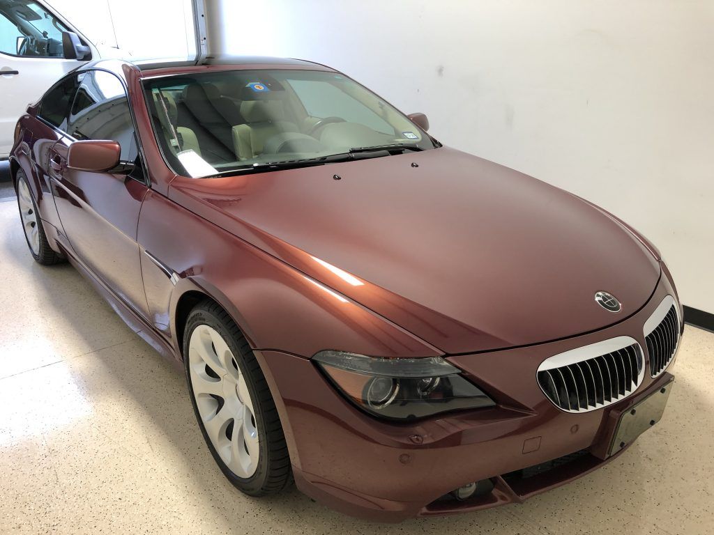 A red bmw is parked in a garage next to a white car.