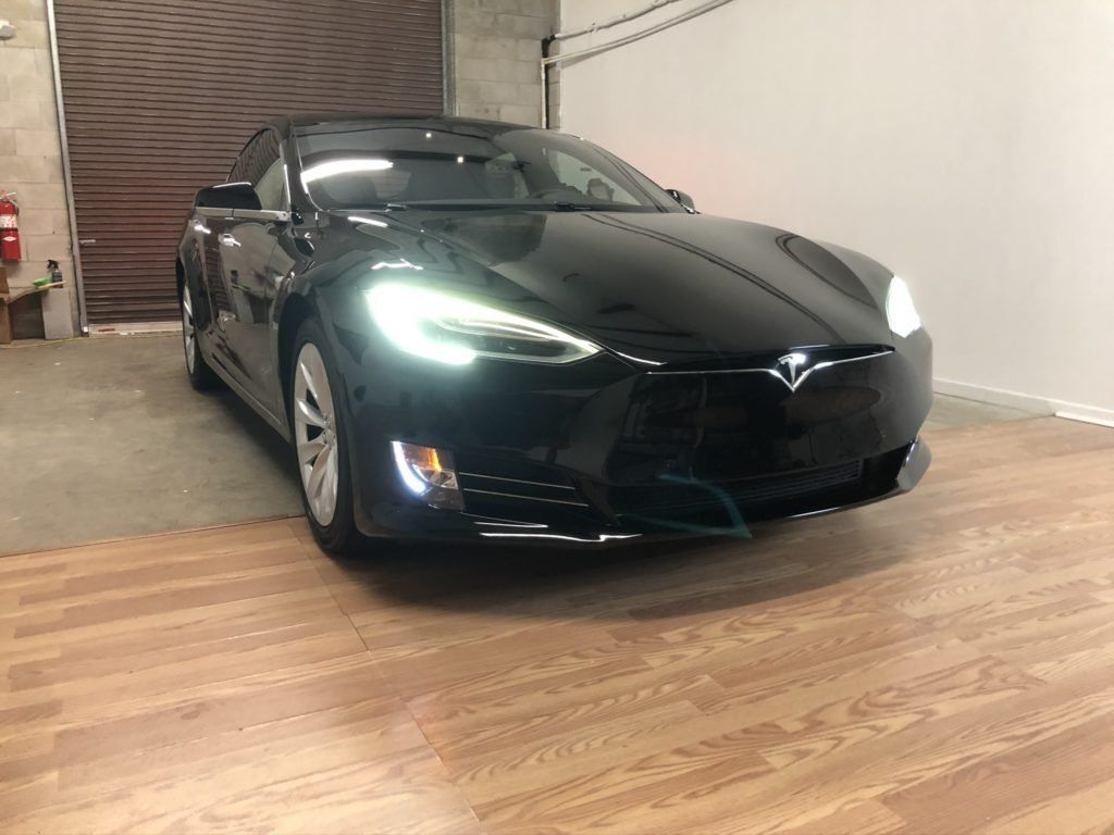 A black tesla model s is parked in a garage.