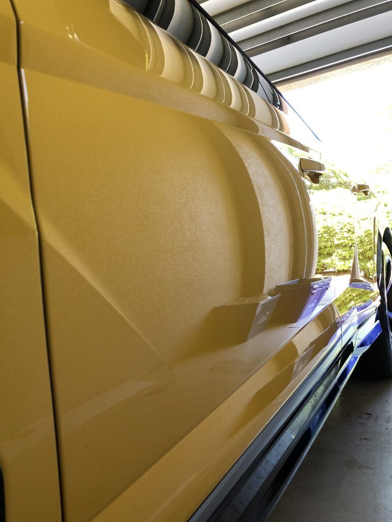 A yellow car is parked in a garage with the door open