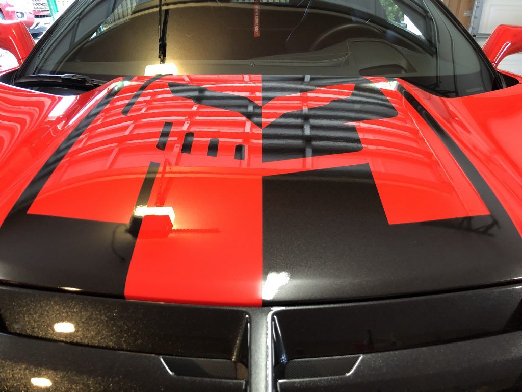 A red car with black stripes on the hood