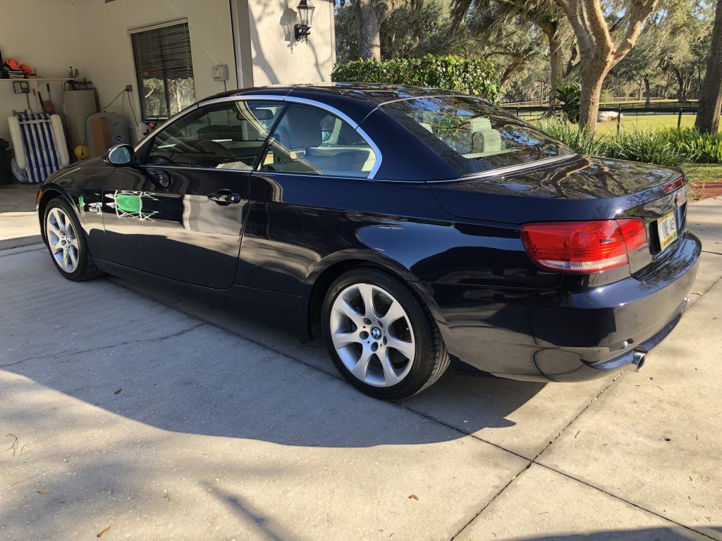 A black bmw 3 series coupe is parked in a driveway.