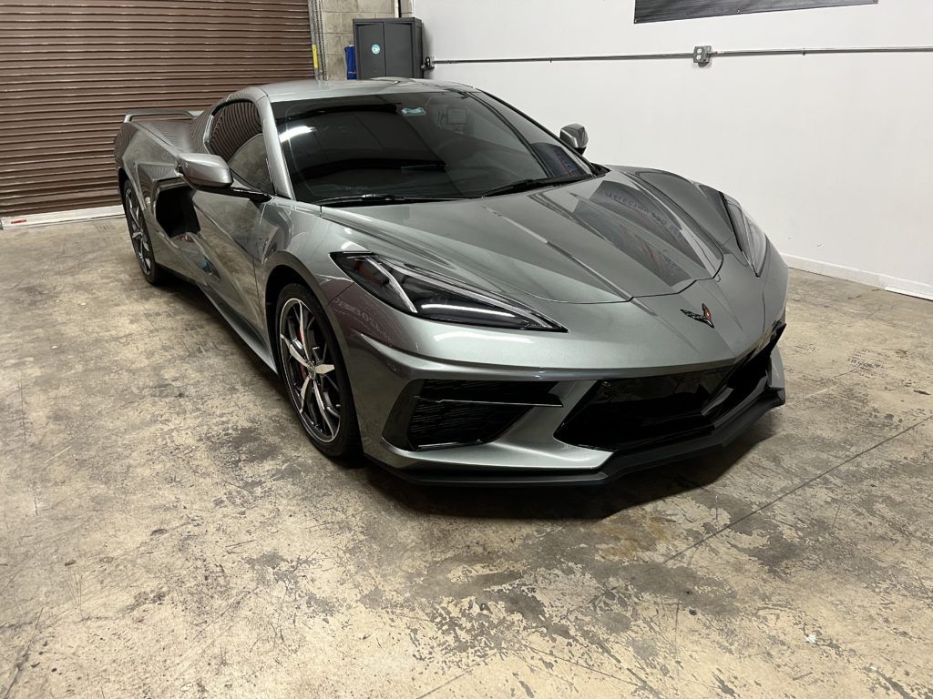 A gray corvette is parked in a garage.