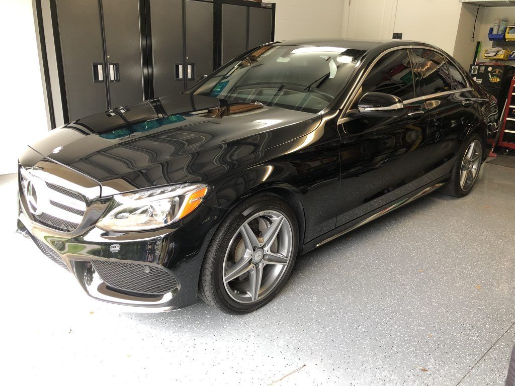 A black mercedes benz is parked in a garage.