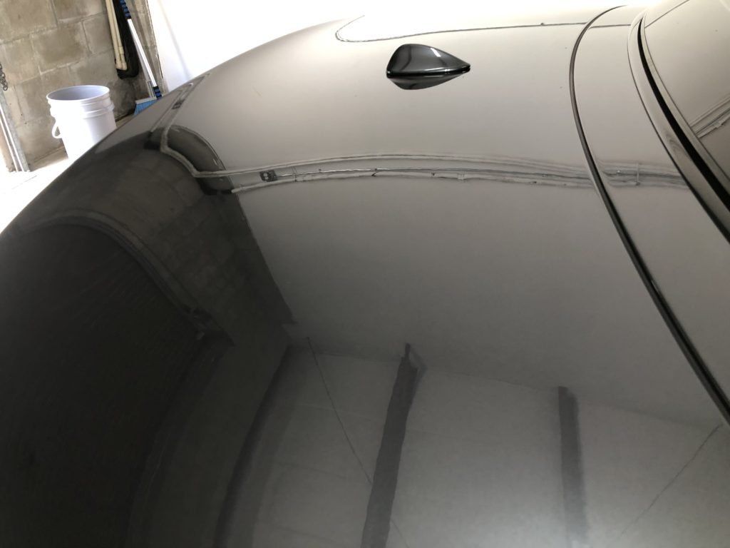 A car with a roof antenna is parked in a garage