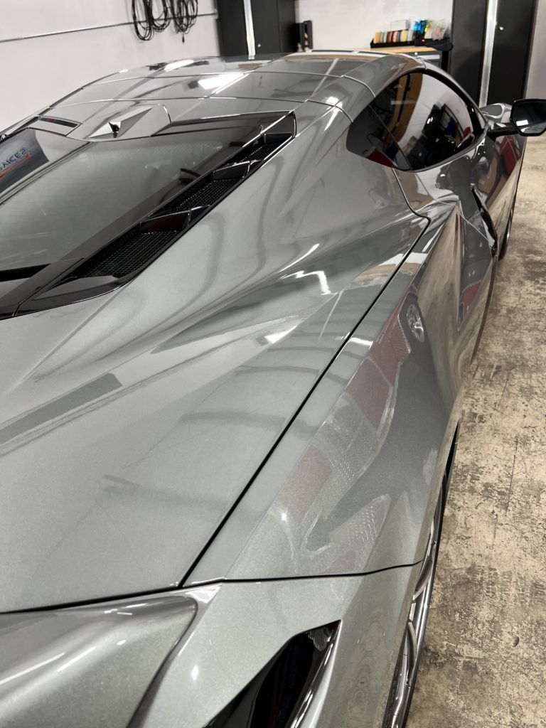 A gray sports car is parked in a garage.