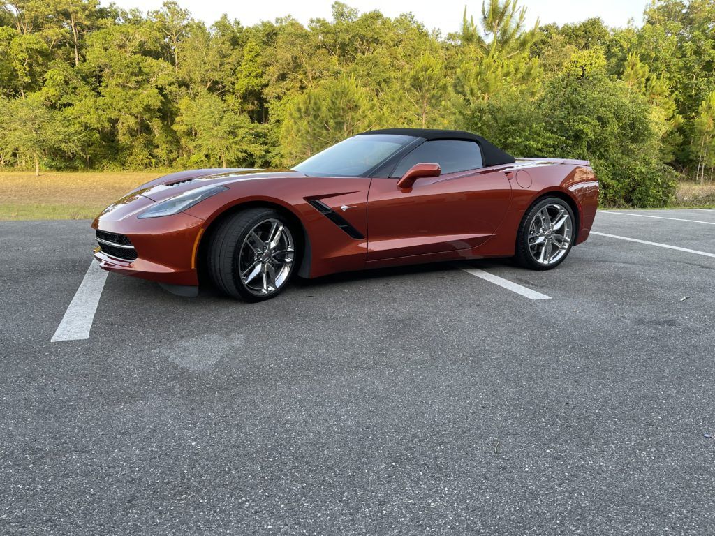 A red corvette convertible is parked in a parking lot.
