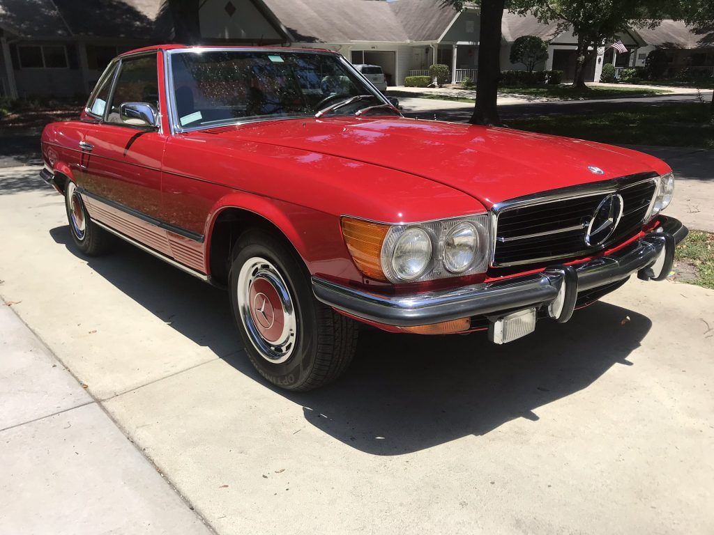 A red mercedes benz sl500 is parked on the side of the road.