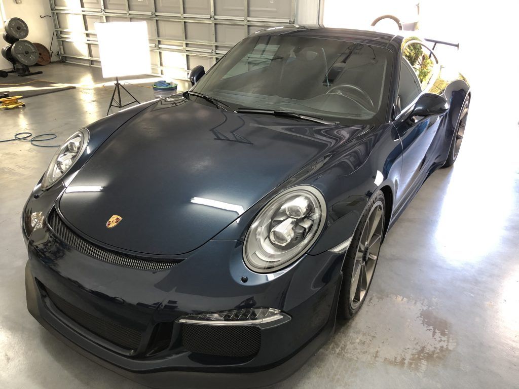 A black porsche 911 is parked in a garage.